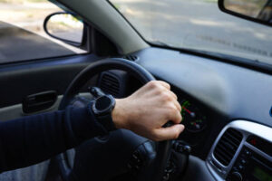 Close-up of driver’s hand on car steering wheel