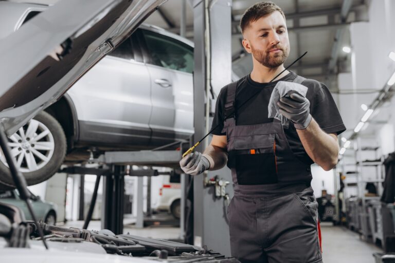 Car mechanic checking the engine oil level in the service center