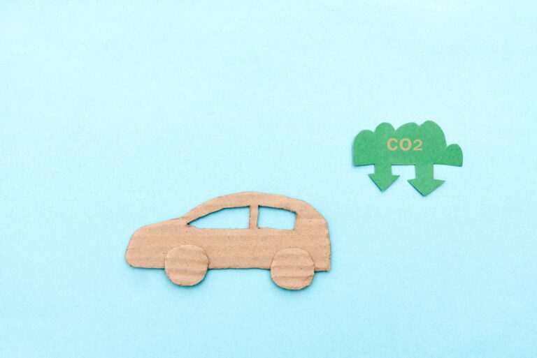 Cardboard car with CO2 symbol on blue background representing low emissions and eco friendly transpo