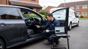 Mobile ECU remapping technician connecting diagnostic laptop to car OBD port on residential driveway in West Midlands