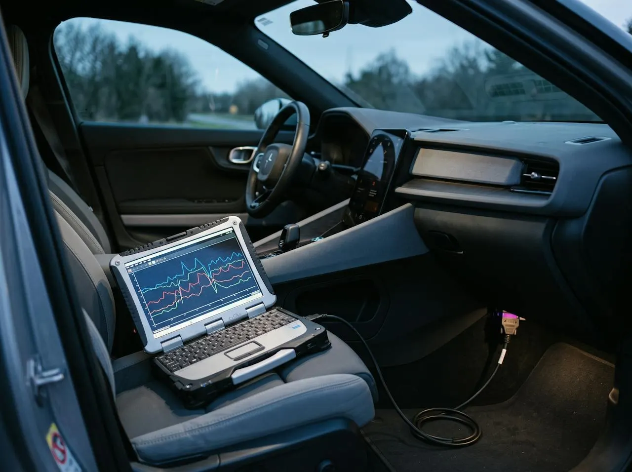 A laptop on a car seat plugged into the diagnostic port